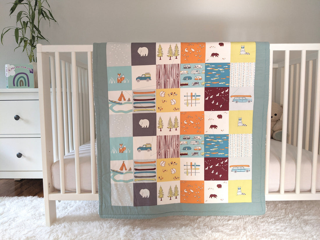 Camping Faux Patches, backed with Fluffy Sherpa, Original Size, Sage Border, hangs over the side of a crib in a nursery