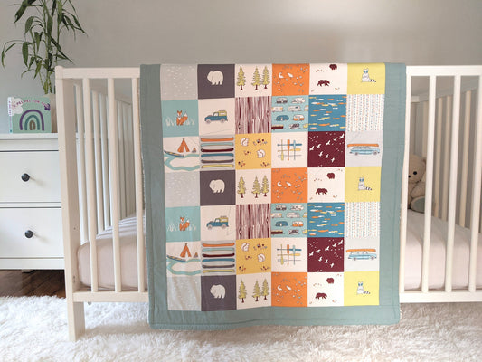 Camping Faux Patches, backed with Fluffy Sherpa, Original Size, Sage Border, hangs over the side of a crib in a nursery