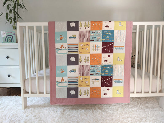 Camping Faux Patches, backed with Fluffy Sherpa, Original Size, Woodrose/ Pink Border, hangs over the side of a crib in a nursery