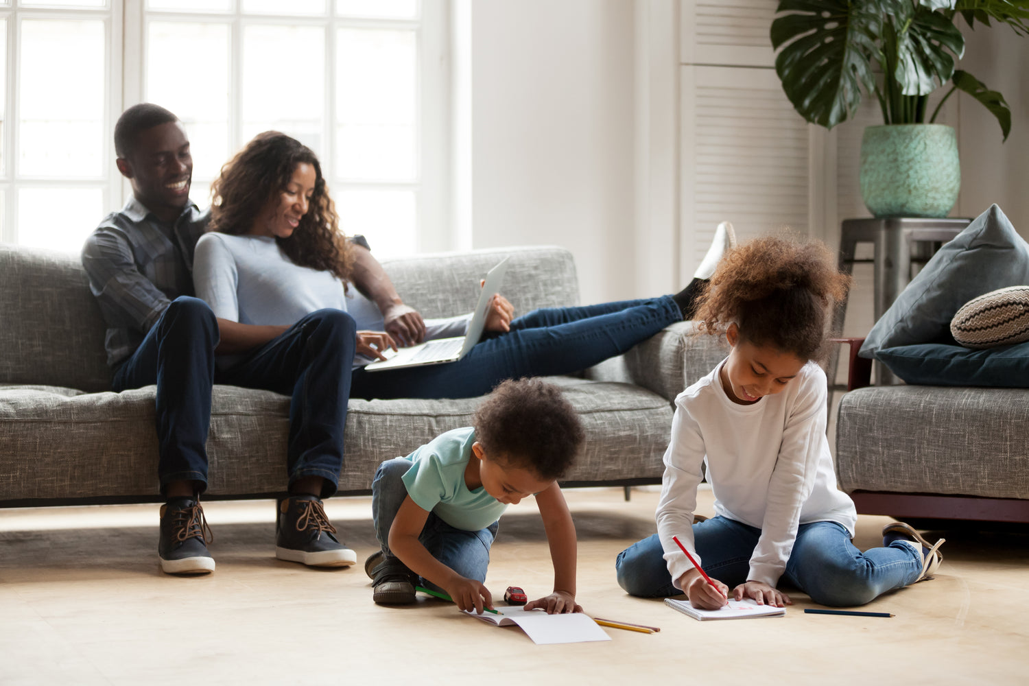 Baby Peipei, reserve a peipei to crowdfund. In the background, a pregnant Black couple are sitting on a couch looking at a laptop. In the foreground, their two children, a toddler boy and older sister, are sitting on the floor and drawing