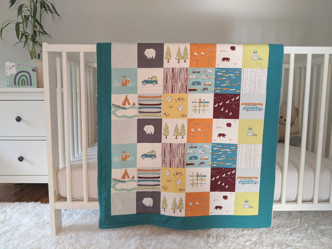 Camping Faux Patches, backed with Fluffy Sherpa, Original Size, Teal Border, hangs over the side of a crib in a nursery