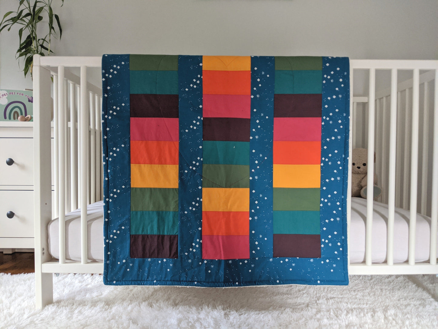Bright Rainbow on Blue Sky, backed with Fluffy Sherpa, Original size, hanging over the side of a crib in a nursery
