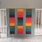 Bright Rainbow on Sage, backed with Fluffy Sherpa, Original, hangs over the side of a crib in a nursery